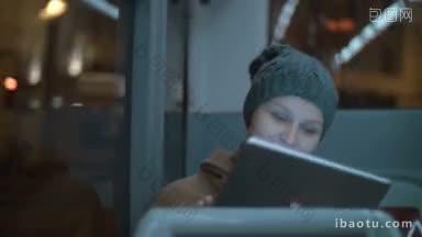 行驶中的公交车上的女乘客一边用平板电脑一边看着窗外